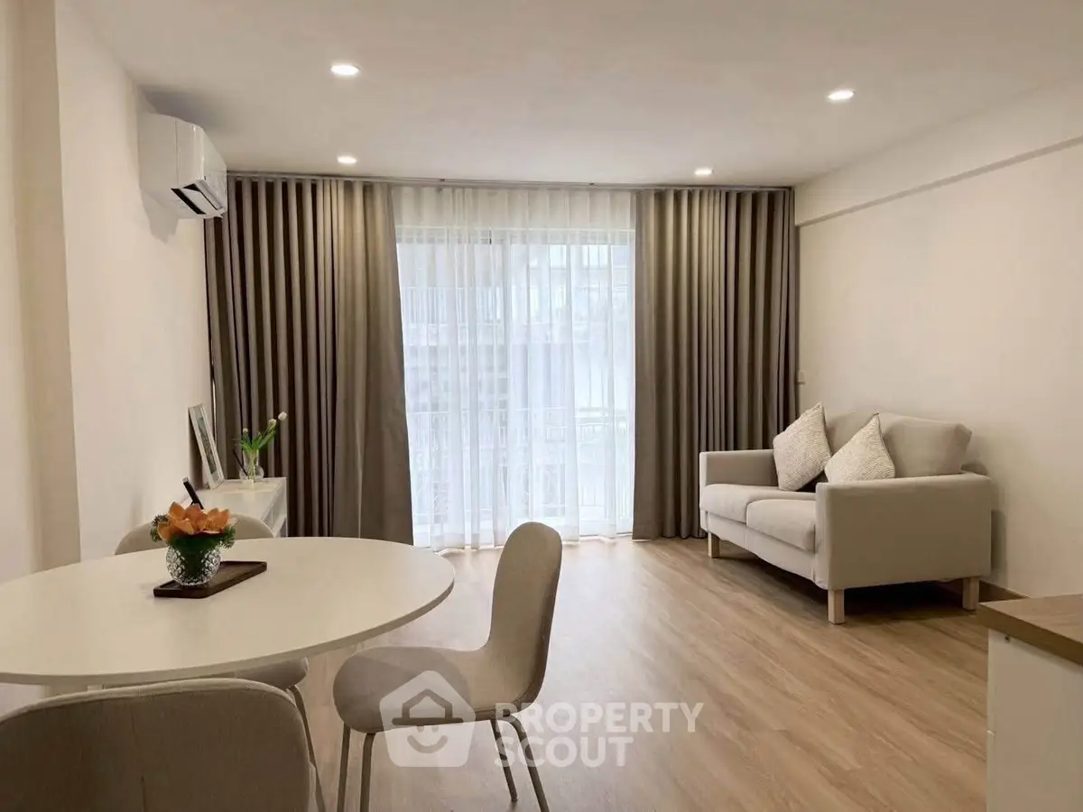 Modern living room with elegant decor and natural light, featuring a cozy sofa and dining area.