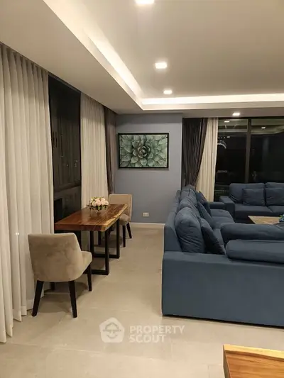 Spacious modern living room with elegant decor and large blue sectional sofa.