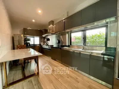 Spacious modern kitchen with sleek cabinetry and dining area, perfect for culinary enthusiasts.