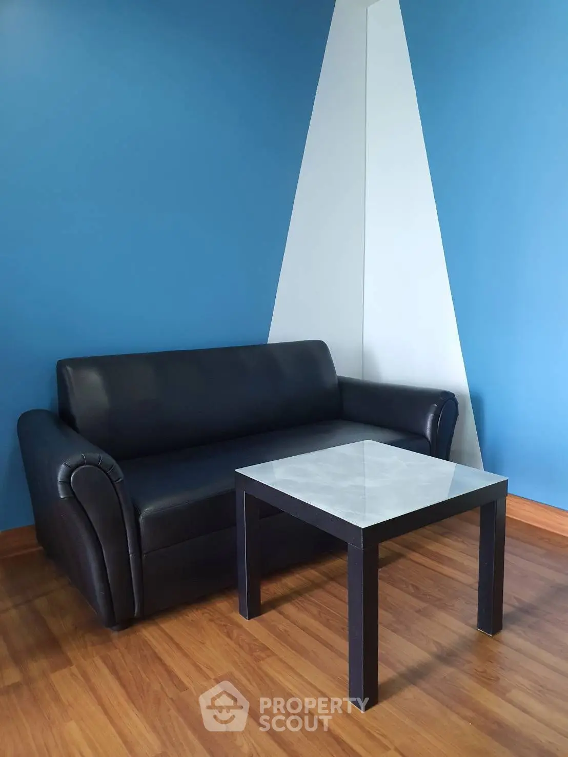 Modern living room with stylish black sofa and sleek coffee table against blue accent wall.