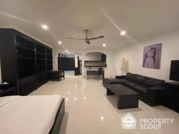 Spacious modern living room with glossy white tiles, elegant black furniture, and a sophisticated ceiling fan, perfect for upscale urban living.