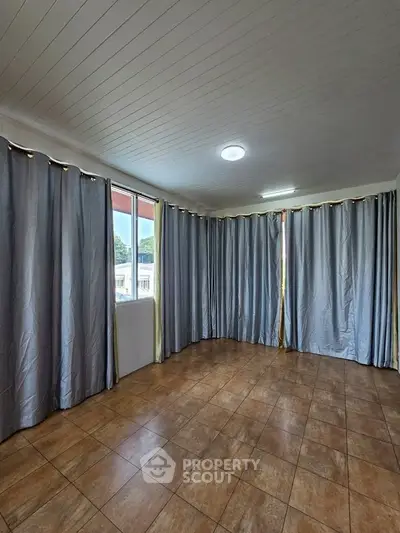 Spacious room with tiled floor and large windows, ideal for versatile living space.