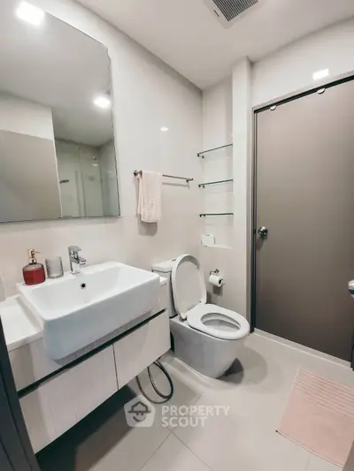 Modern bathroom with sleek fixtures and minimalist design, featuring a spacious sink and elegant mirror.