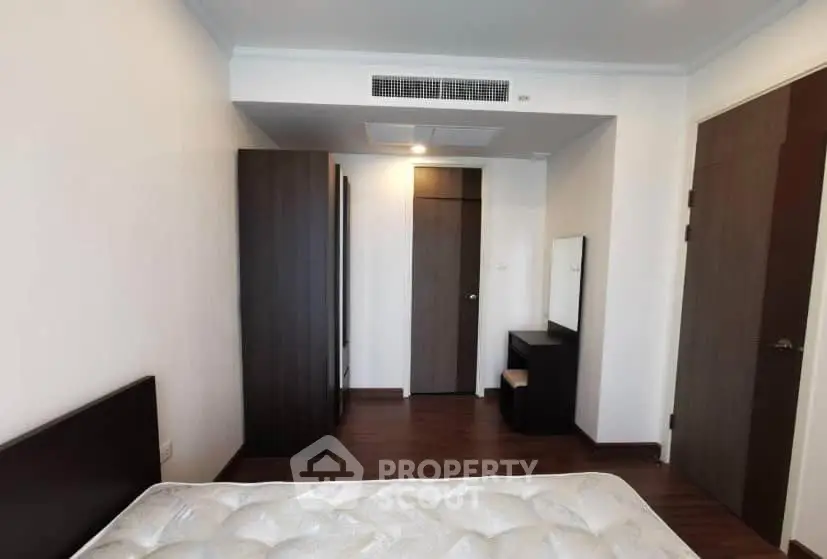 Spacious bedroom with modern furniture and wooden flooring in a stylish apartment.