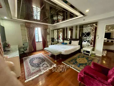 Luxurious bedroom with elegant decor, mirrored walls, and hardwood floors.