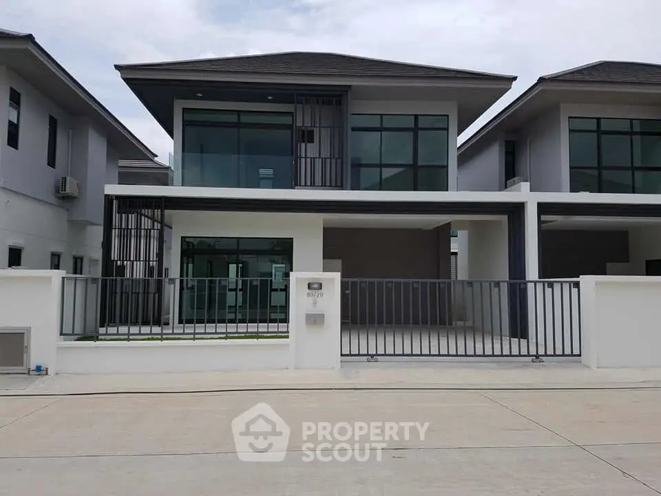 Modern two-story house with sleek design and large windows in a suburban neighborhood.