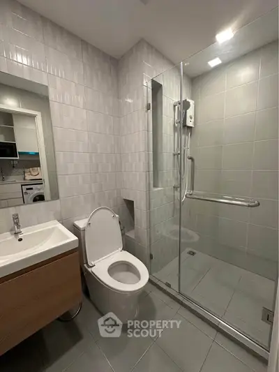 Modern bathroom with glass shower and sleek fixtures in contemporary apartment.