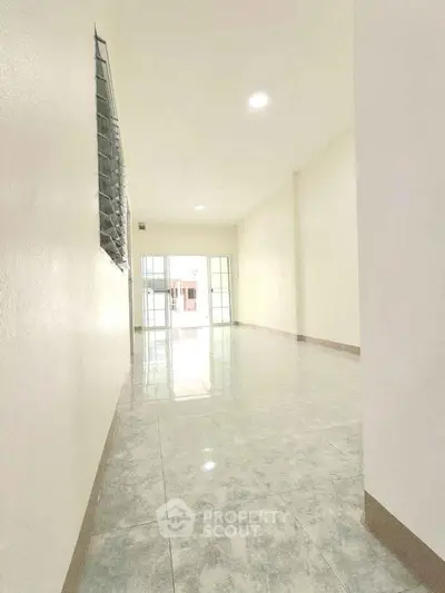 Spacious empty room with tiled flooring and large window, ideal for customization.