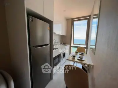 Modern kitchen with ocean view, featuring sleek appliances and cozy dining area.