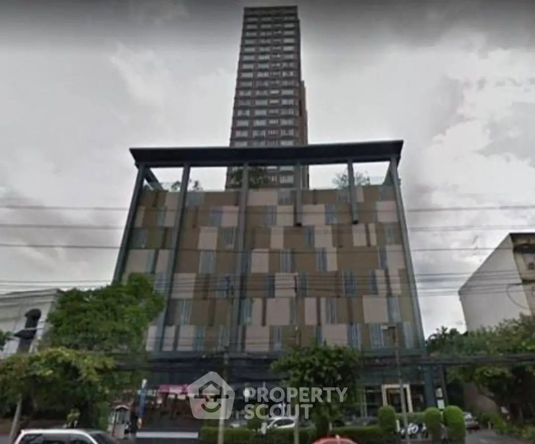 Modern high-rise building with unique architectural design and lush greenery.