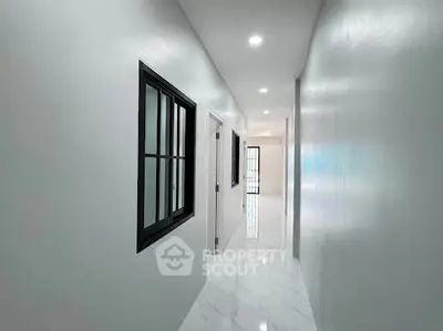 Sleek modern hallway with glossy white floors and black-framed windows, perfect for contemporary living.