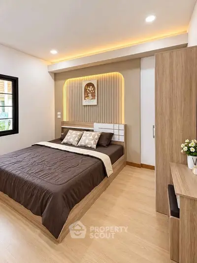 Modern bedroom with stylish decor and cozy lighting, featuring a comfortable bed and wooden furniture.