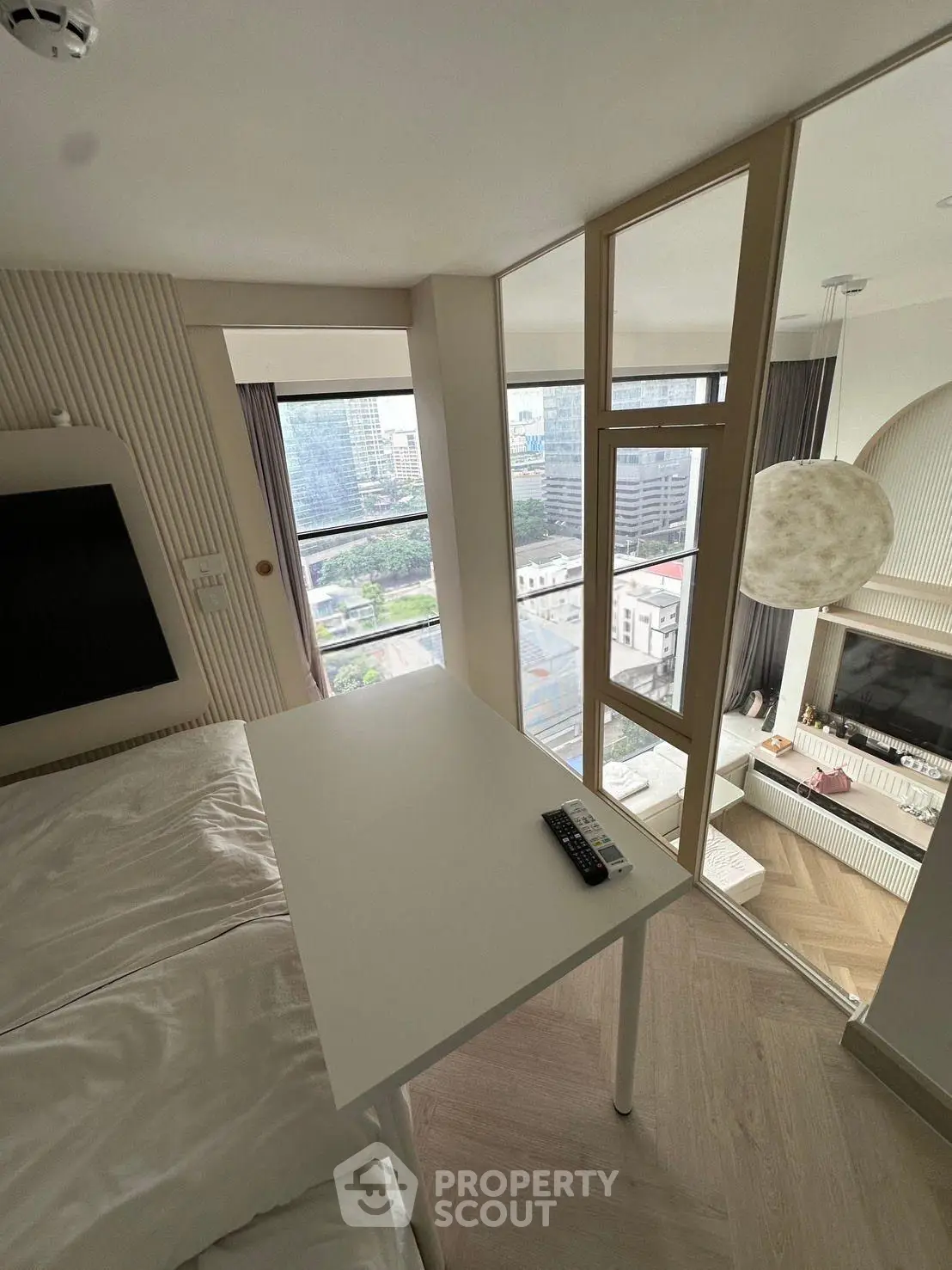 Modern studio apartment with large windows and city view, featuring a cozy living area and sleek design.