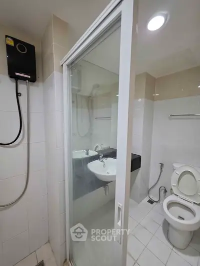 Modern bathroom with glass shower door and white fixtures in a contemporary apartment.
