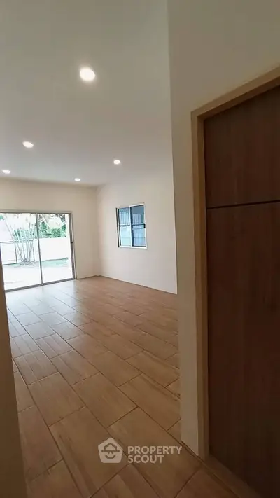 Spacious empty room with wooden flooring and large windows