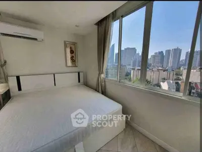 Bright bedroom with large window offering stunning city view, featuring modern decor and air conditioning.