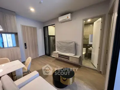 Modern living room with open layout, featuring sleek furniture and integrated kitchen appliances.