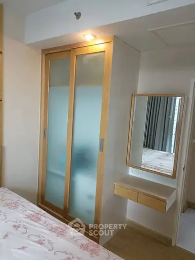 Cozy bedroom with built-in wardrobe and vanity mirror, perfect for modern living.