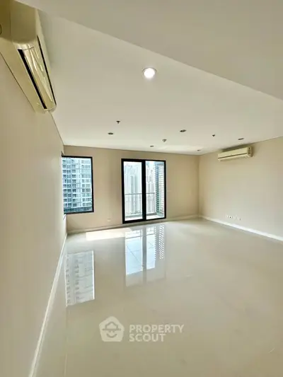 Spacious modern living room with large windows and city view in high-rise apartment.