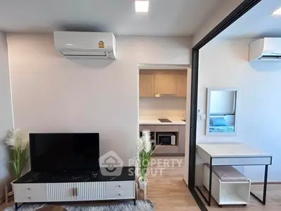 Modern living room with sleek TV stand and air conditioning, adjacent to a compact kitchen area.