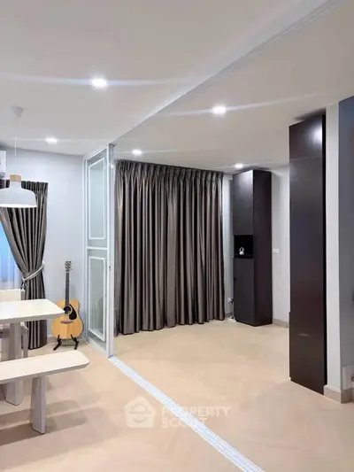 Modern living room with elegant curtains and stylish lighting, featuring a cozy dining area and a guitar for ambiance.