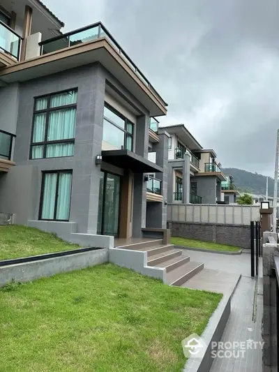 Modern multi-story residential building with large windows and green lawn