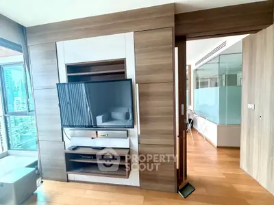 Modern living room with sleek wooden paneling and large TV, offering a glimpse of a stylish urban apartment.