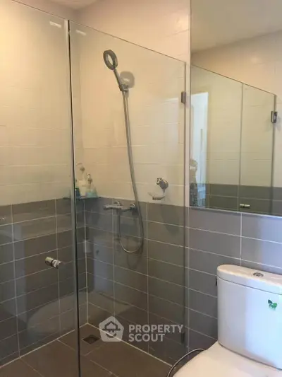 Modern bathroom with glass shower enclosure and sleek tile design.