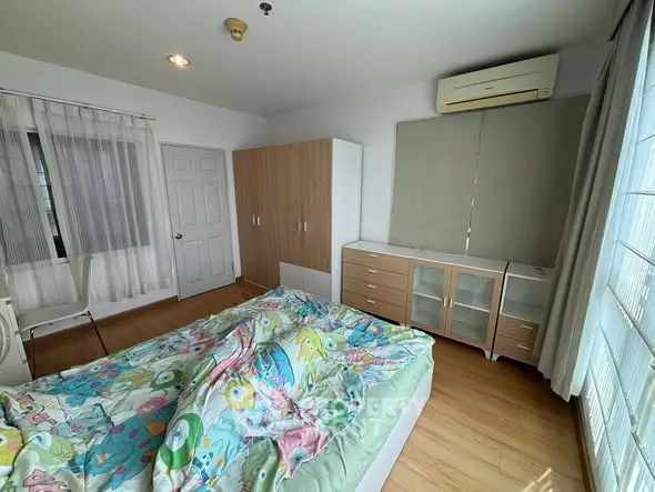 Spacious bedroom with colorful bedding and ample natural light.