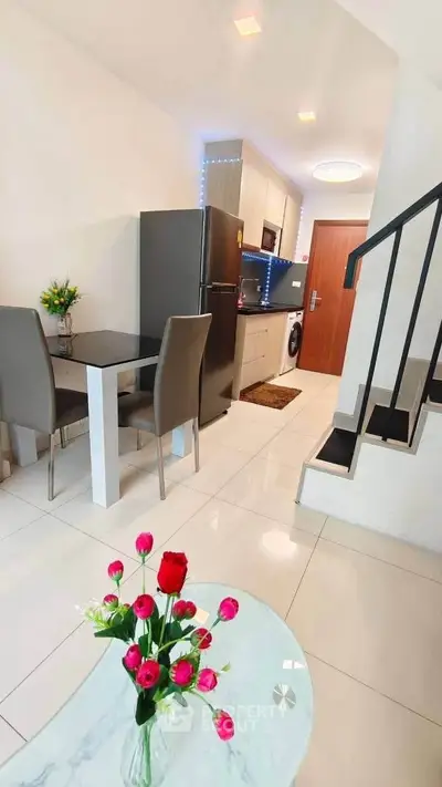 Modern open-plan kitchen and dining area with sleek design and elegant staircase