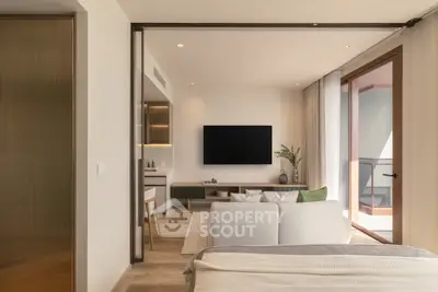 Modern living room with open layout and balcony access, featuring sleek furniture and a wall-mounted TV.