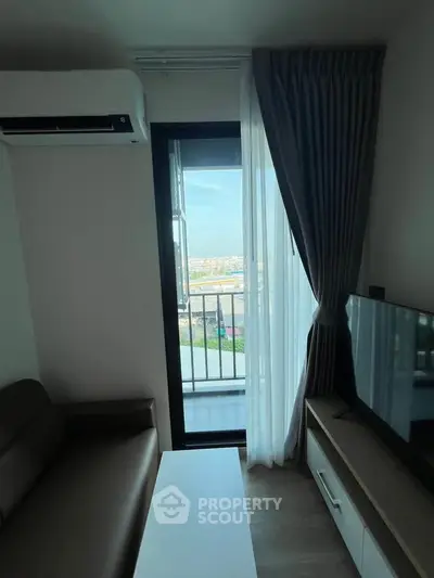 Modern living room with balcony view, featuring sleek furniture and natural light.