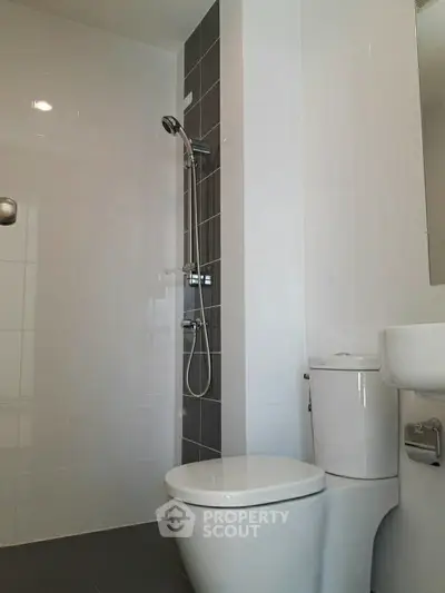 Modern bathroom with sleek shower and toilet in contemporary apartment.
