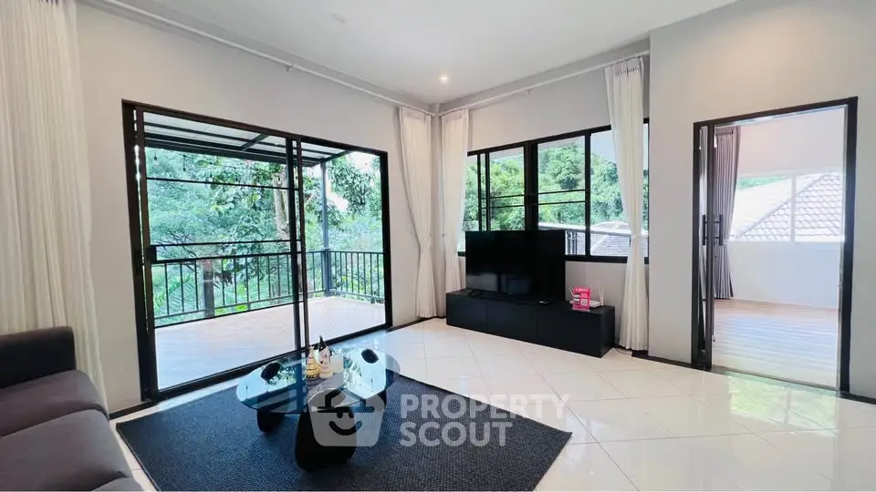 Spacious living room with large windows and balcony access, modern decor and serene view.