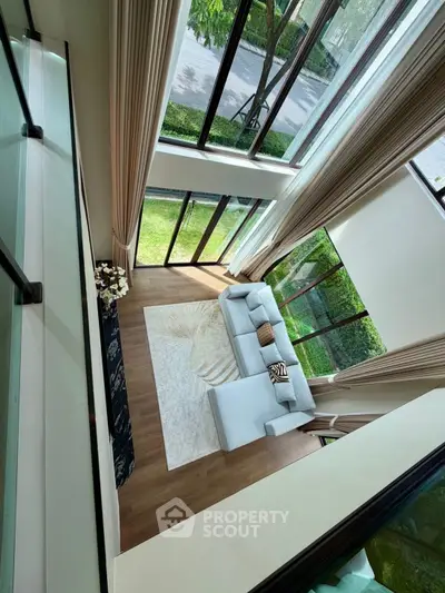Stunning double-height living room with floor-to-ceiling windows and elegant decor.