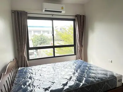 Cozy bedroom with large window and natural light, featuring a comfortable bed and air conditioning.