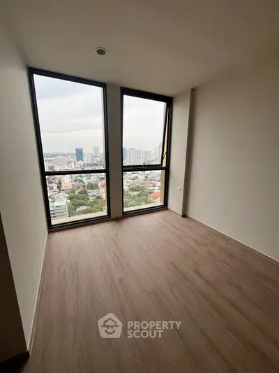 Spacious room with floor-to-ceiling windows offering stunning city views.