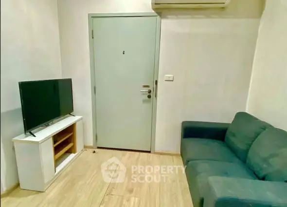 Cozy living room with modern sofa and flat-screen TV, perfect for relaxation.