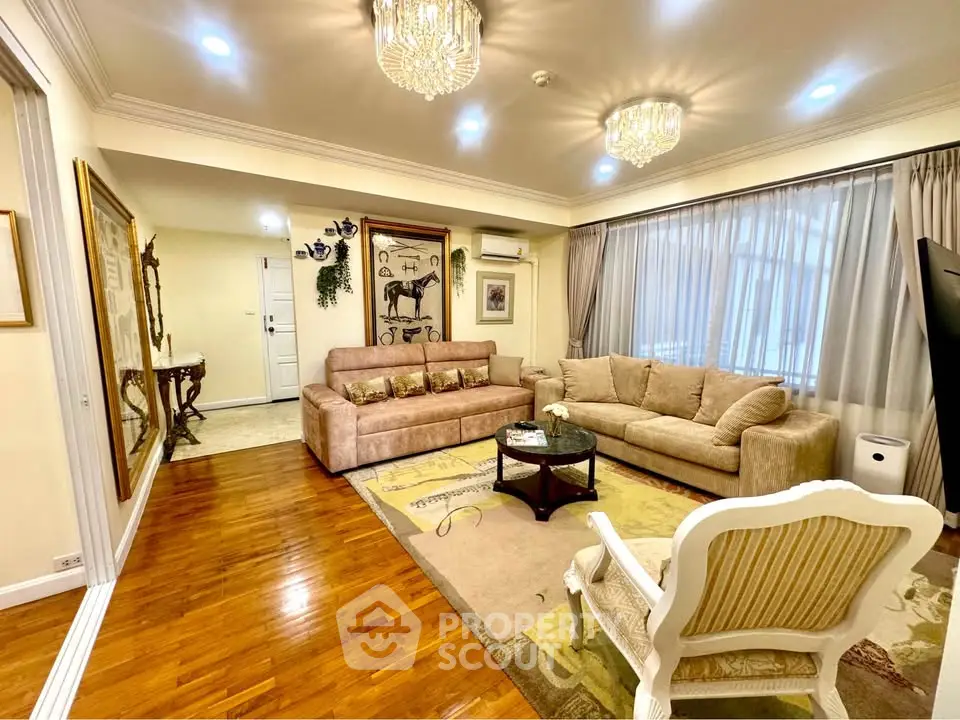 Elegant living room with plush sofas, hardwood floors, and chandelier lighting in a cozy apartment.