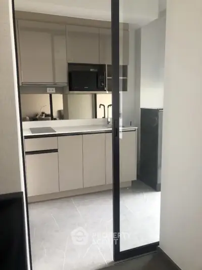 Modern compact kitchen with sleek cabinetry and built-in appliances in a contemporary apartment.