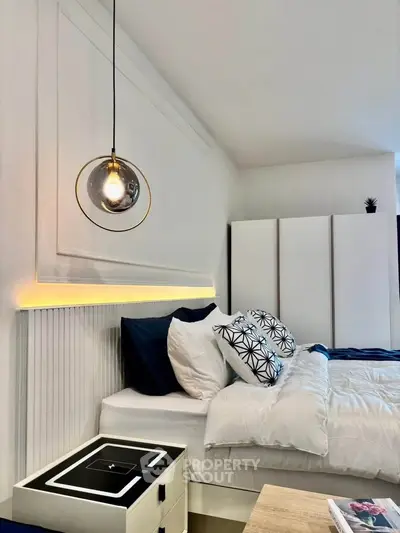 Modern bedroom with stylish lighting and cozy bedding in a contemporary apartment.