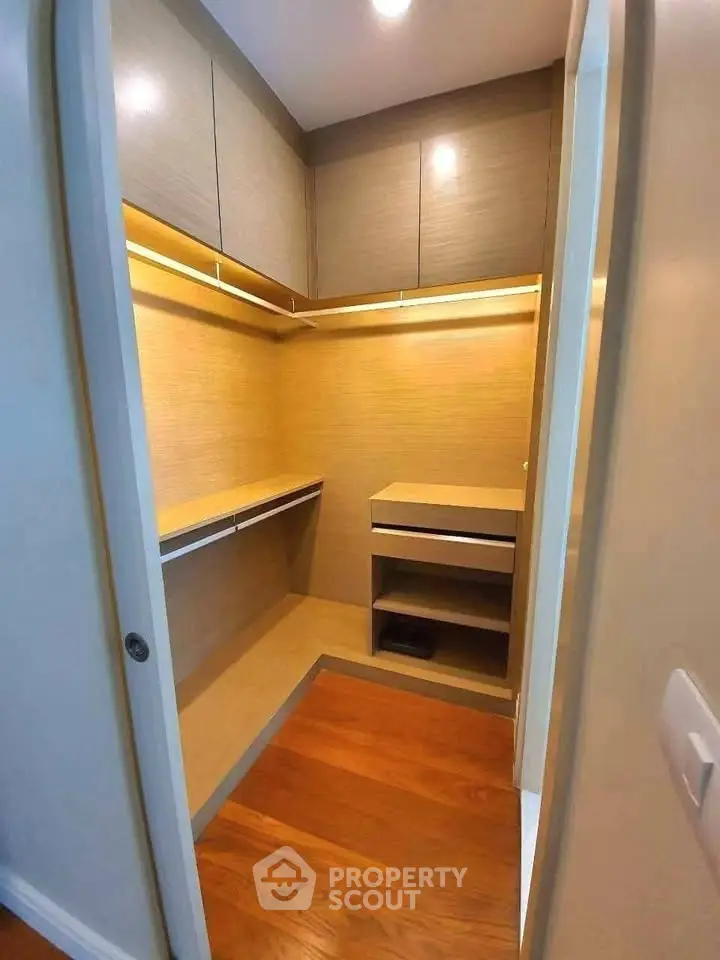 Spacious walk-in closet with wooden flooring and ample storage space.