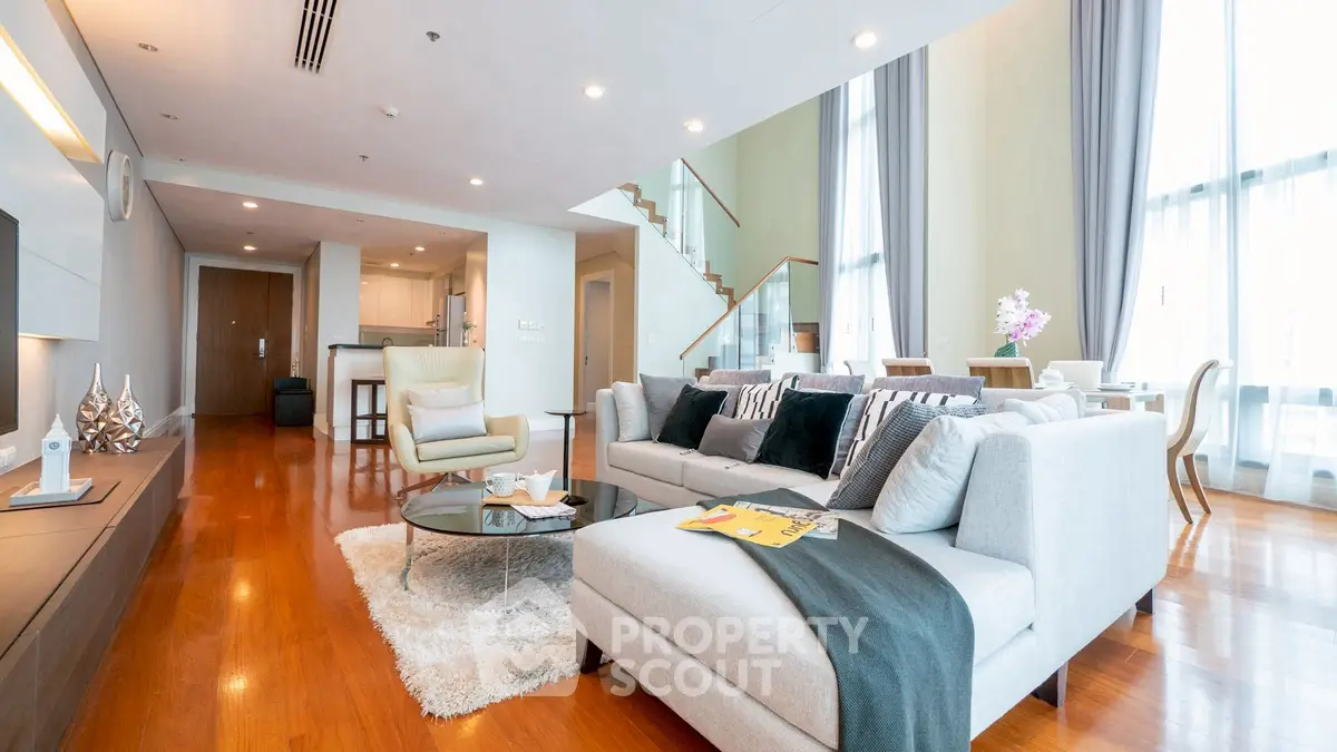 Luxurious open-plan living room with modern decor and elegant staircase