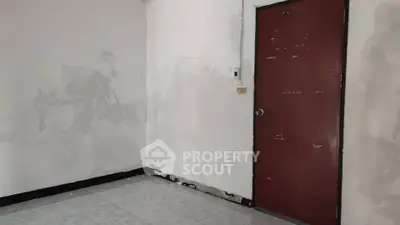 Unfurnished room with plain walls and a red door, ideal for customization.