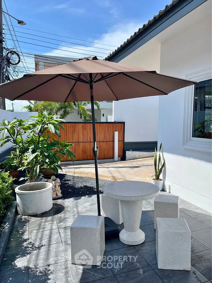 Charming outdoor patio with umbrella and modern seating in a stylish home exterior.