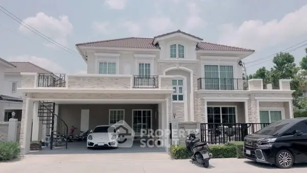 Luxurious two-story house with spacious driveway and modern vehicles parked in front.