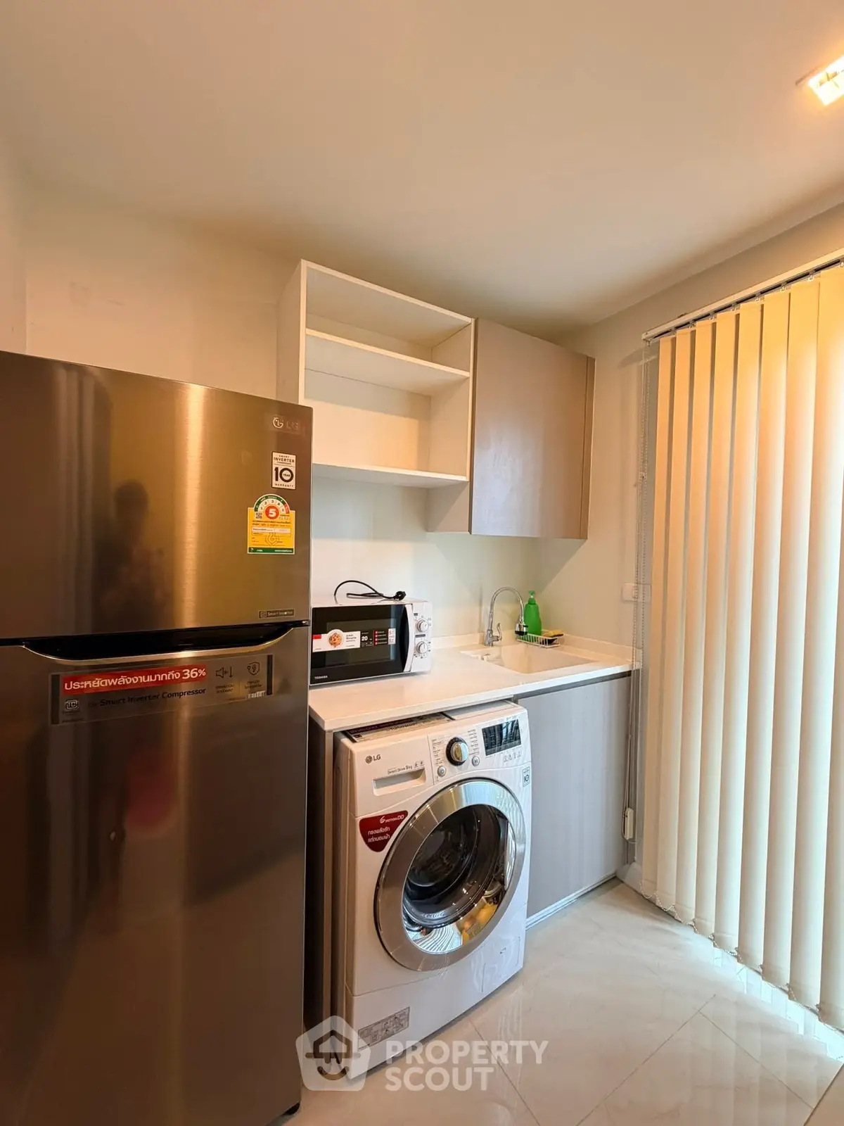 Modern kitchen with stainless steel fridge and washing machine in a cozy apartment.