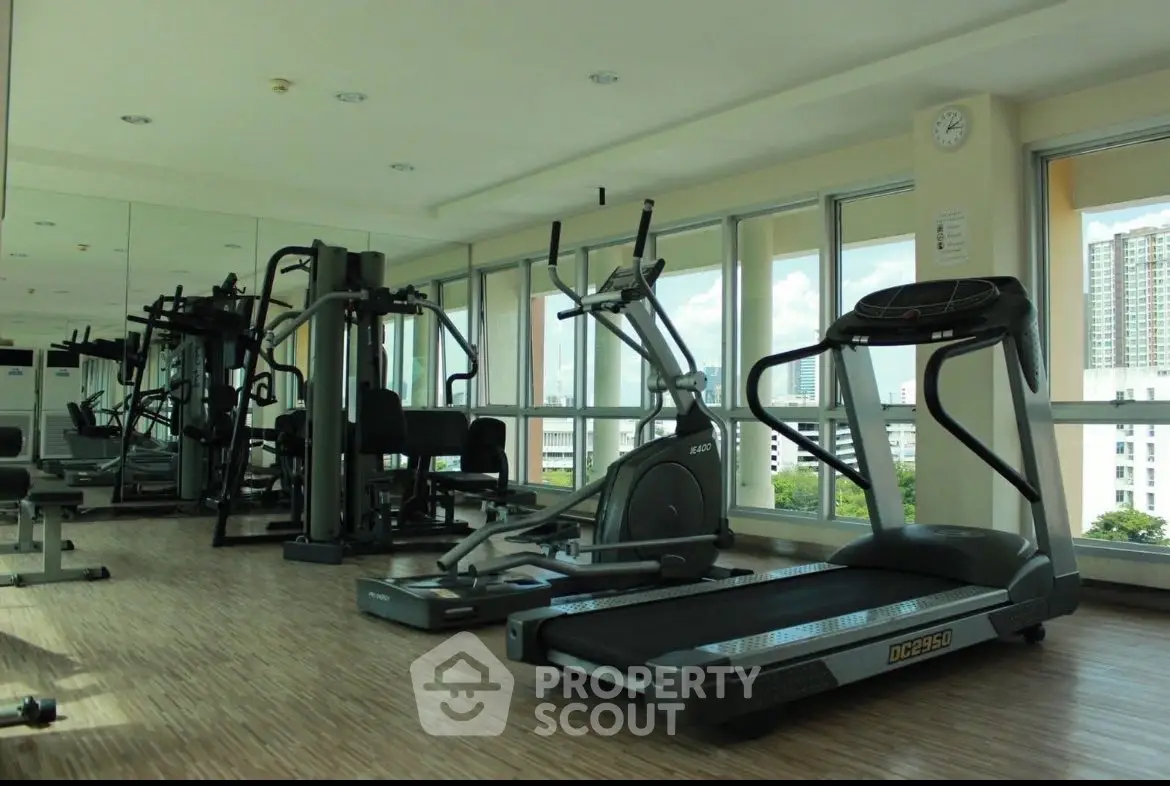 Spacious gym with modern equipment and city view in luxury apartment complex.
