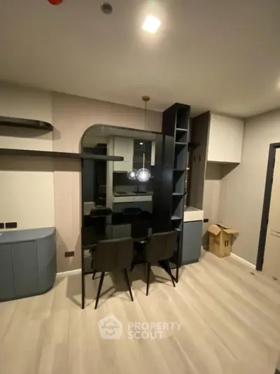 Modern dining area with sleek black table and chairs, stylish lighting, and contemporary shelving.