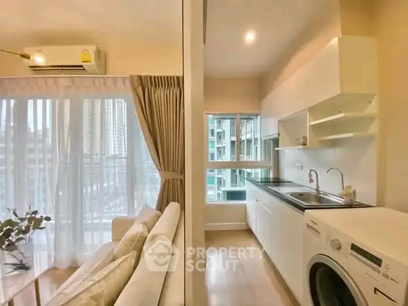Modern apartment with open kitchen and cozy living area, featuring large windows and natural light.